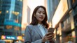 © Lucija - On-the-go Korean businesswoman with smartphone, city streets
