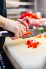 Wall Mural - Chefs woman hands chopping red pepper on board