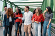 © Lomb - A group of multicultural friends walk relaxed and smiling on a city bridge, enjoying a day together.