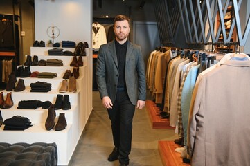 Wall Mural - Businessman in classic vest against row of suits in shop