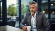 A focused photo captures a cropped view of a mature entrepreneur in a jacket, taking a coffee break at the office. 