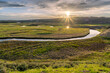 A river meander through a green open meadow with the low sun reflecting off the water at sunset, Trout Creek, Hayden Valley, Yellowstone National Park, Wyoming
