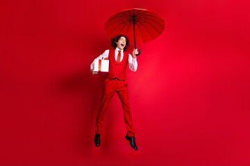 Poster - Full body photo of overjoyed birthday guy special delivery gift box flying umbrella wear classic outfit isolated on red color background