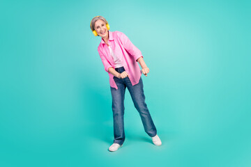 Sticker - Full body size photo of funny woman wear pink shirt and jeans looks like hipster with wireless headphones isolated on cyan color background