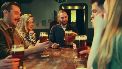 Wall Mural - Positive, cheerful young people meeting at bar, saying toasts, clinking beer glasses. Celebration, holiday. Concept of leisure time, friendship, fun and joy, youth, enjoyment