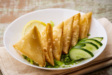 Deep Fried Sambosa Cheese samosa triangle wrap with lime and cucumber served in dish isolated on table top view of arabic food