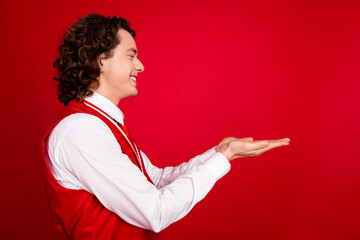 Poster - Side profile photo of young teenage gentleman guy curly hair gentleman working like waiter in restaurant isolated on red color background