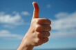 © shiva - A close-up of a thumb up gesture against a clear blue sky, symbolizing approval, agreement or success. Ideal for business, customer service and travel themes