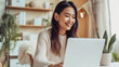 © olindana - Attractive young Asian woman sitting in a cafe working at her laptop. Freelance distant work business management concept