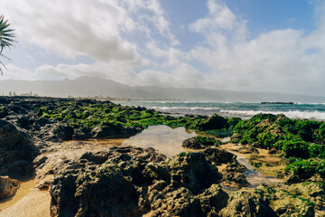 beautiful beach with black rocks on a stormy day on oahu in hawaii