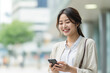 © wazamai - Smiling Asian businesswoman using smartphone in the city