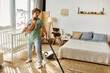 © LIGHTFIELD STUDIOS - man multitasking housework and childcare, father vacuuming hardwood floor with infant son in arms