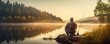 the fisherman sitting on top of a rock and watching a mountain lake,