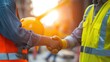 two construction workers shake hands close up