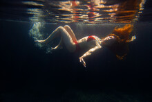 A Beautiful Sporty Girl Poses Underwater With Loose Hair Against The Bright Rays Of The Sun From The Surface.