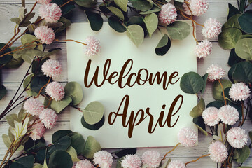 Canvas Print - Welcome April text message with flower decoration on wooden background