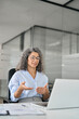 © insta_photos - Busy professional mature lady hr manager, older middle aged business woman in office looking at laptop computer talking having hybrid online conference call work meeting or remote job interview.
