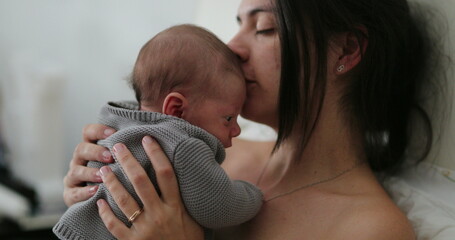 candid mother holding newborn baby in bed showing love care and affection