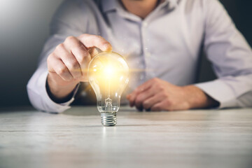 Canvas Print - a man holding a light bulb in his hand