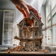 A man's hand destroys a house. Concept of demolition of housing and houses. Renovation old home and construction project. Tearing Down a Houses.