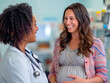 © Ирина Селина - An African American female gynecologist consults a pregnant young Hispanic female patient in her office