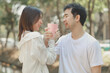 © kamiphotos - Happy young Asian couple in a park, Portrait of smiling couple near beautiful nature outdoors, lifestyle, Cheerful couple hugging each other, Young couple enjoying the sunny day at park
