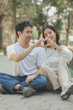 © kamiphotos - Happy young Asian couple in a park, Portrait of smiling couple near beautiful nature outdoors, lifestyle, Cheerful couple hugging each other, Young couple enjoying the sunny day at park