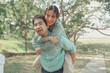 © kamiphotos - Happy young Asian couple in a park, Portrait of smiling couple near beautiful nature outdoors, lifestyle, Cheerful couple hugging each other, Young couple enjoying the sunny day at park