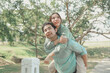 © kamiphotos - Happy young Asian couple in a park, Portrait of smiling couple near beautiful nature outdoors, lifestyle, Cheerful couple hugging each other, Young couple enjoying the sunny day at park