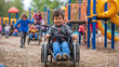 Child in wheel chair with a disability playing on an accessible playground.
