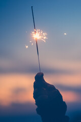 Wall Mural - close up of woman looking at sparkler the night of the new year at the evening alone and lonely - lady playing with sparkler outdoors