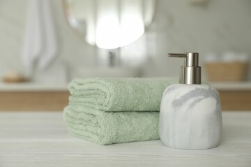 Poster - Clean towels and soap dispenser on white wooden table in bathroom