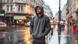 © khoobi's ART - On a city street corner in the rain, a romantic guy wears a charcoal gray hoodie, the wet sheen enhancing the hoodie's urban chic, mockup