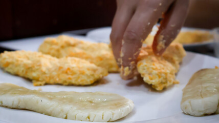 Wall Mural - Close-up of a woman making fried banana by coating the banana in golden bread crumb to then be fried. Ideal for food blogs, cooking concepts, food enthusiasts, and cooking-themed designs. 