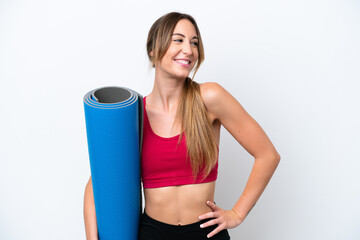 Wall Mural - Young sport woman going to yoga classes while holding a mat isolated on white background posing with arms at hip and smiling