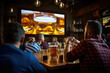 © yanapopovaiv - men in a pub sit at tables with glasses of beer, there is advertising on a large TV screen, rear view from the back