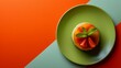 A vibrant dessert presentation featuring a round orange jelly topped with fresh mint and strawberry slices on a green plate, set against a dual-tone orange and green background