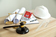 © Worawith - Wooden gavel, house and yellow helmet