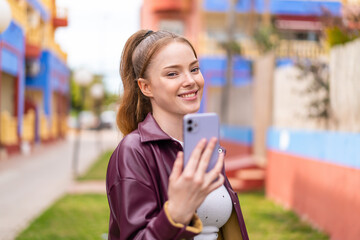 Canvas Print - Young pretty girl using mobile phone at outdoors with happy expression