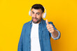 Caucasian man over isolated yellow background listening music and with thumb up
