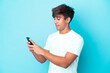 © luismolinero - Young caucasian man isolated on blue background sending a message or email with the mobile