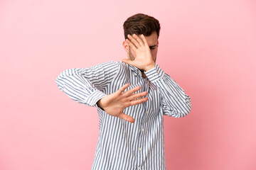 Wall Mural - Young caucasian handsome man isolated on pink background nervous stretching hands to the front