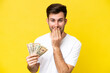 © luismolinero - Young caucasian man taking a lot of money isolated on yellow background happy and smiling covering mouth with hand
