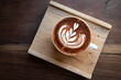 Latte art on hot chocolate on wooden plate flat lay