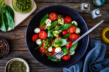 Wall Mural - Caprese salad with pesto sauce on wooden board
