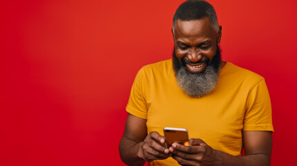 Sticker - bearded older man with a top knot hairstyle, laughing and looking at his phone, wearing a yellow t-shirt against a solid red background