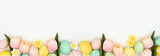 Fototapeta Uliczki - Easter eggs and flower decorations. Top view bottom border against a white banner background. Copy space.