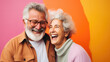 Smiling elderly couple in love, hugging and smiling on a colorful background. Active senior lifestyle concept 