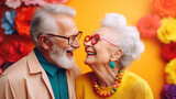 Fototapeta  - Smiling elderly couple wearing glasses in love, hugging and smiling on a colorful background. Active senior lifestyle concept 