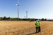 © Jordi Mora - Team of engineers standing in the field inspecting the operation of wind turbines.